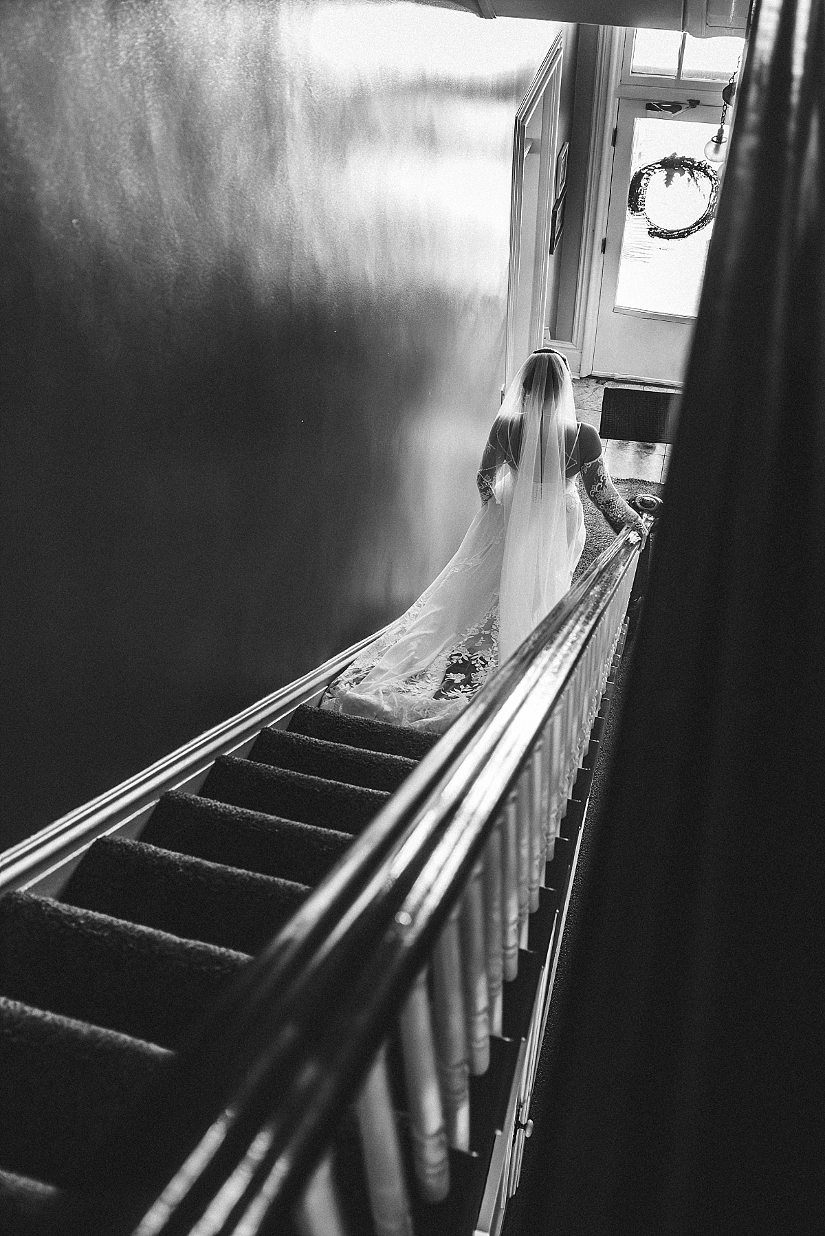 Black and white photo of Grace walking down the staircase in her wedding dress