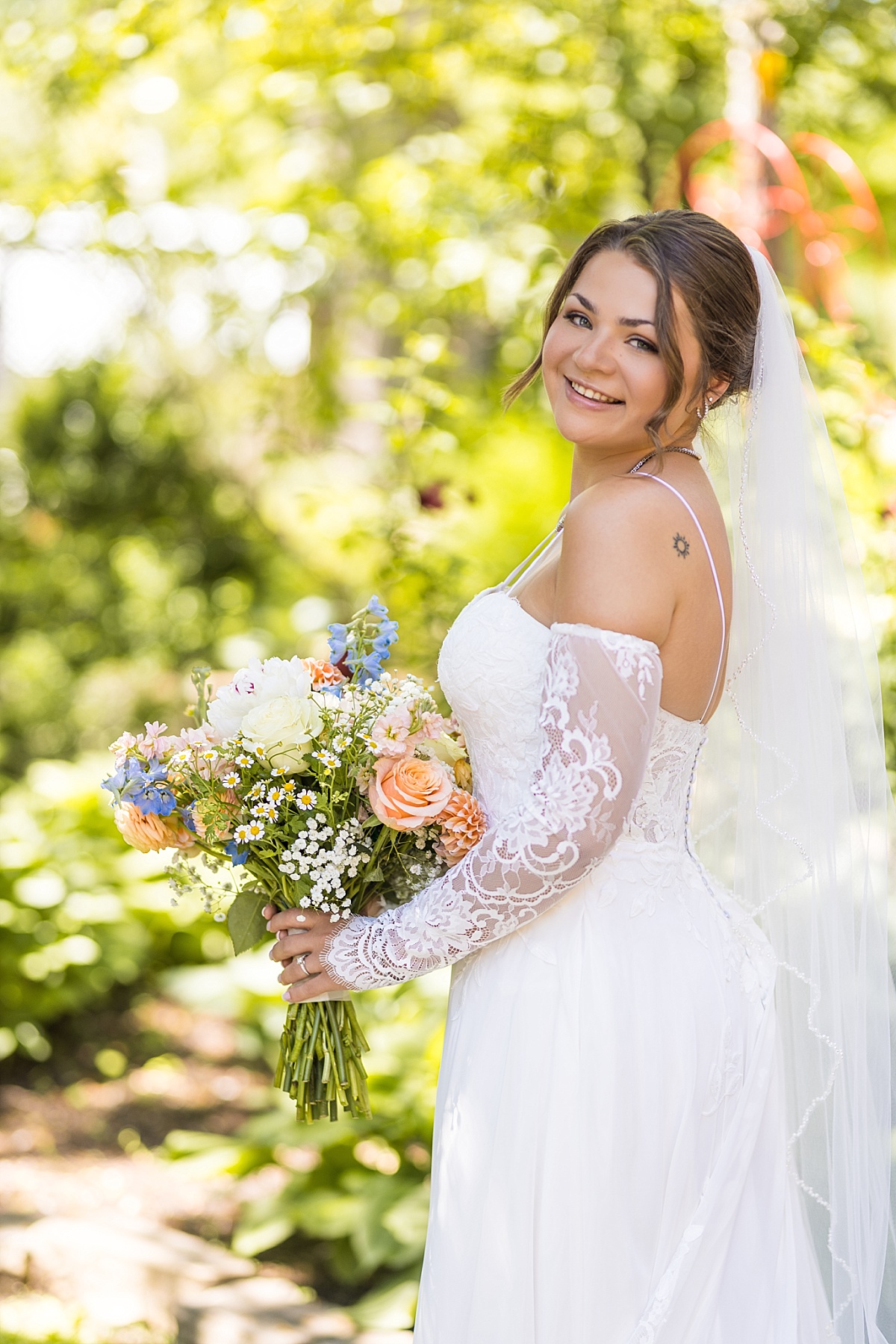 Bridal portrait of Grace holding her bouquet in a sunny garden at the Main St Inn