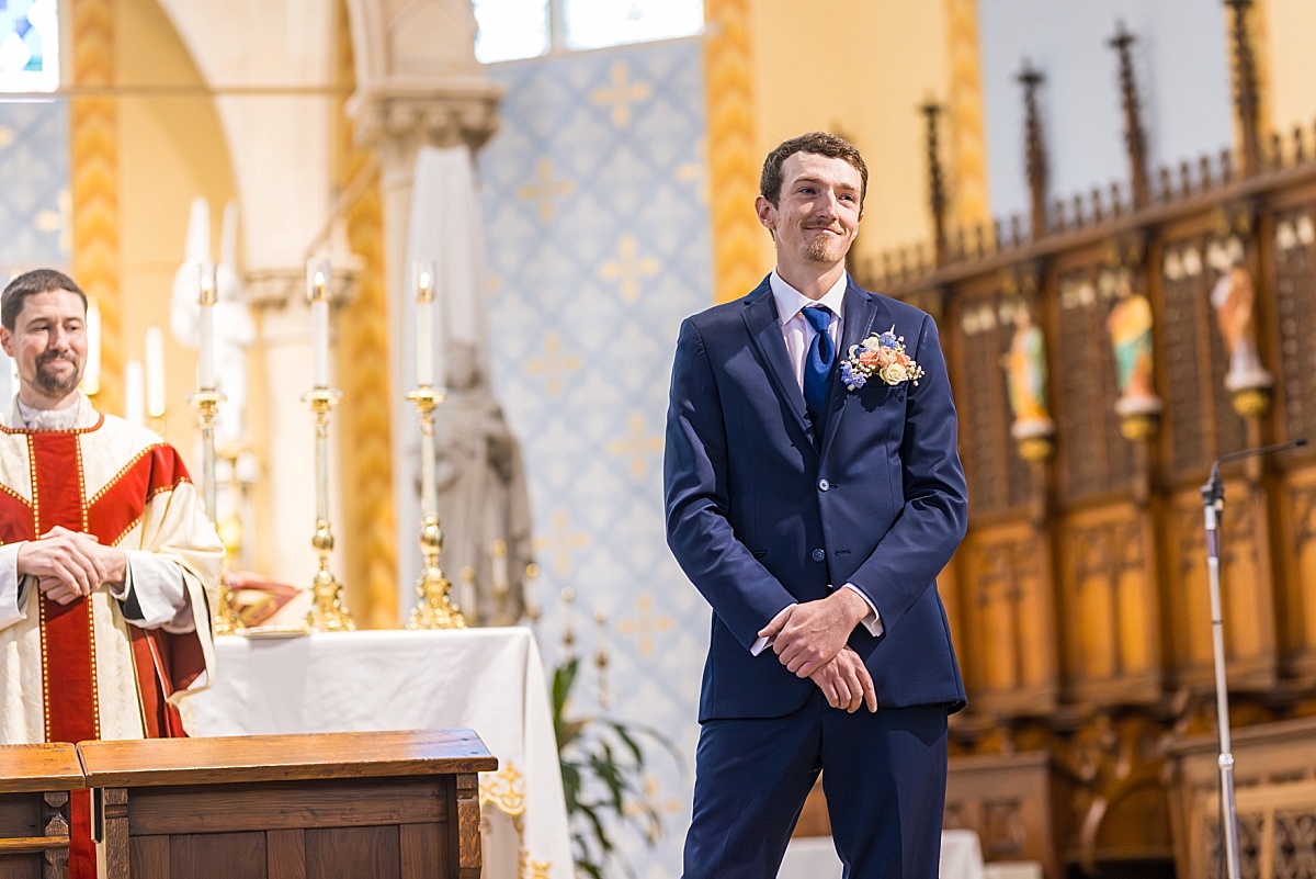 Alex smiles at the altar during the wedding ceremony at Ste. Genevieve Catholic Church