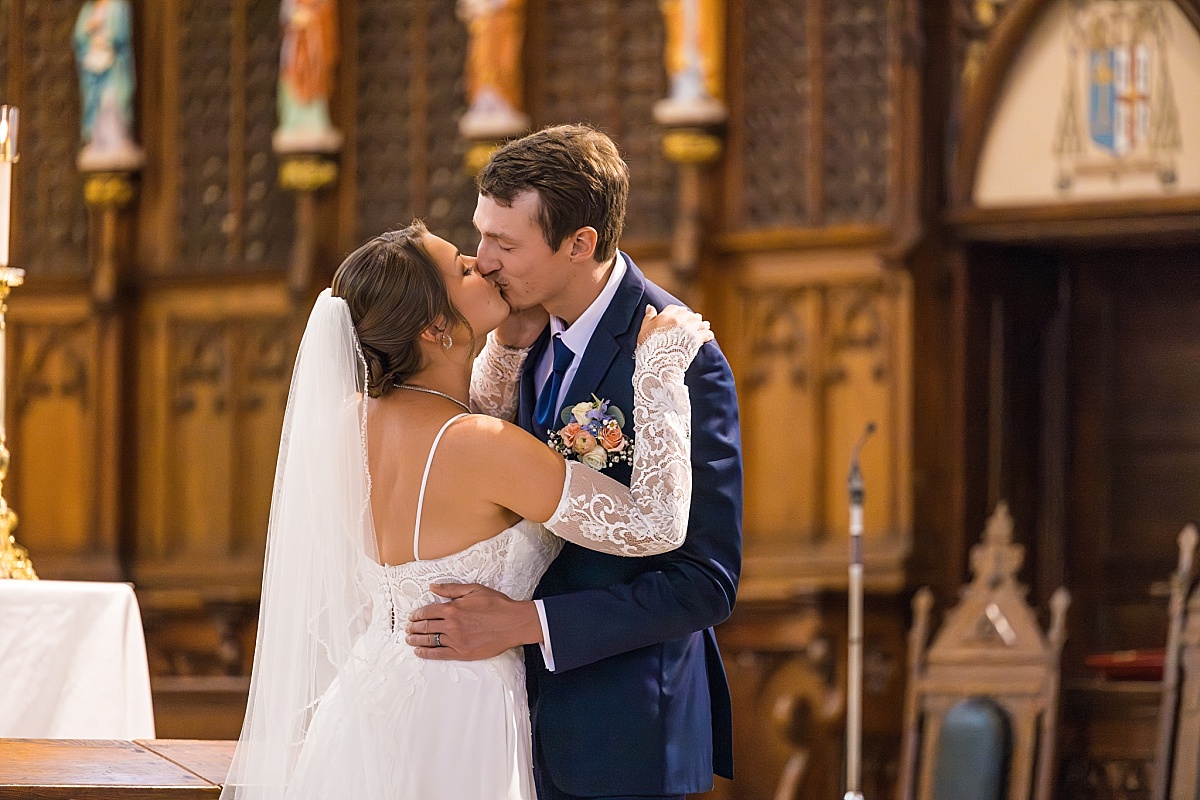 Grace and Alex hold kiss during their wedding ceremony at Ste. Genevieve Catholic Church
