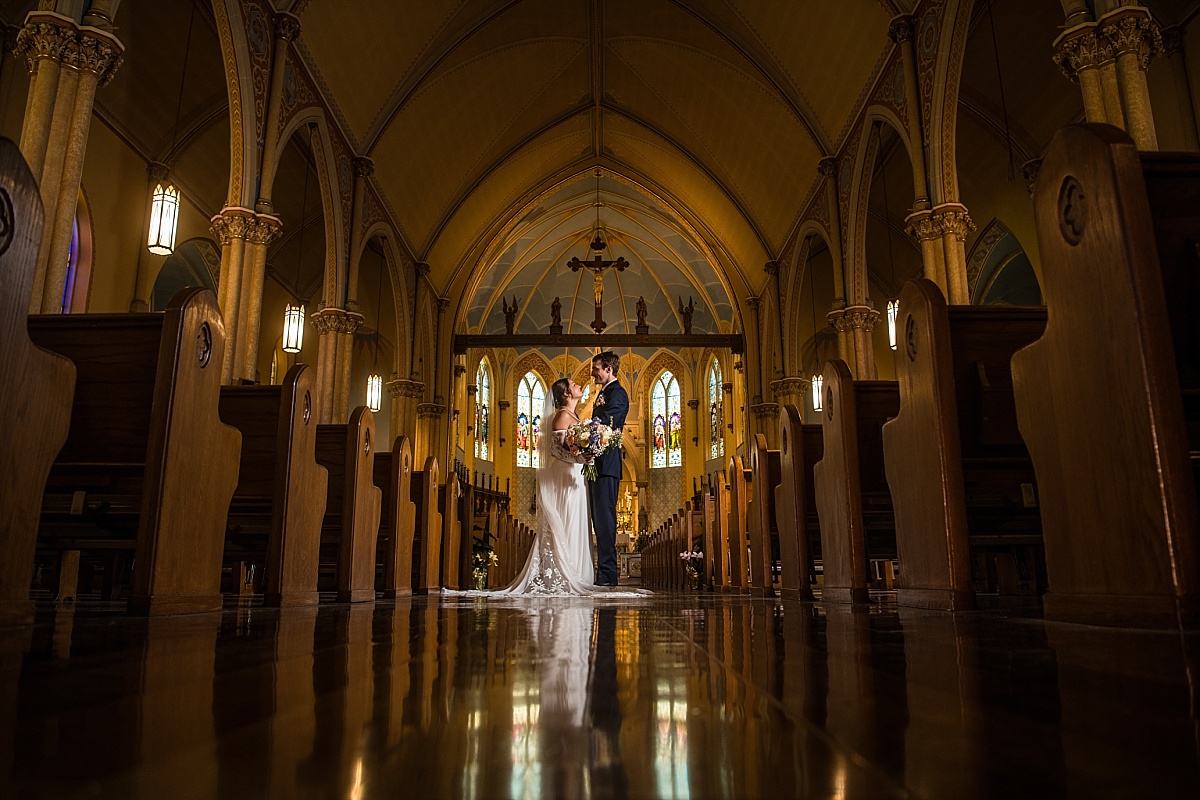 Grace and Alex pose in the aisle of Ste. Genevieve Catholic Church after the ceremony