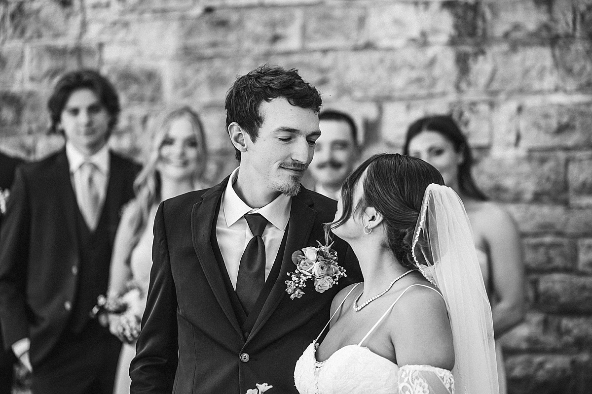 Black and white portrait of Grace and Alex with their wedding party behind them