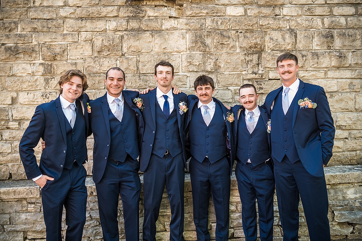 Alex and his groomsmen pose against a stone wall in downtown Ste. Genevieve