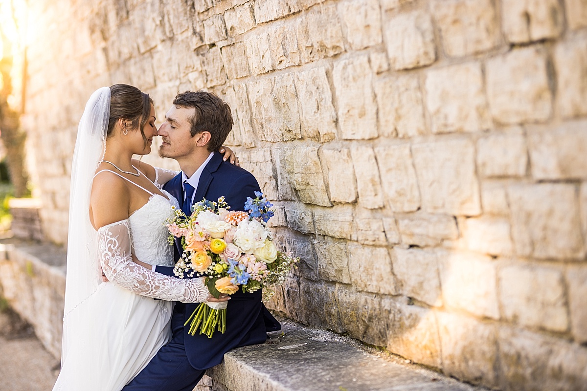 Grace and Alex sit together on a stone ledge for downtown Ste. Genevieve wedding portraits