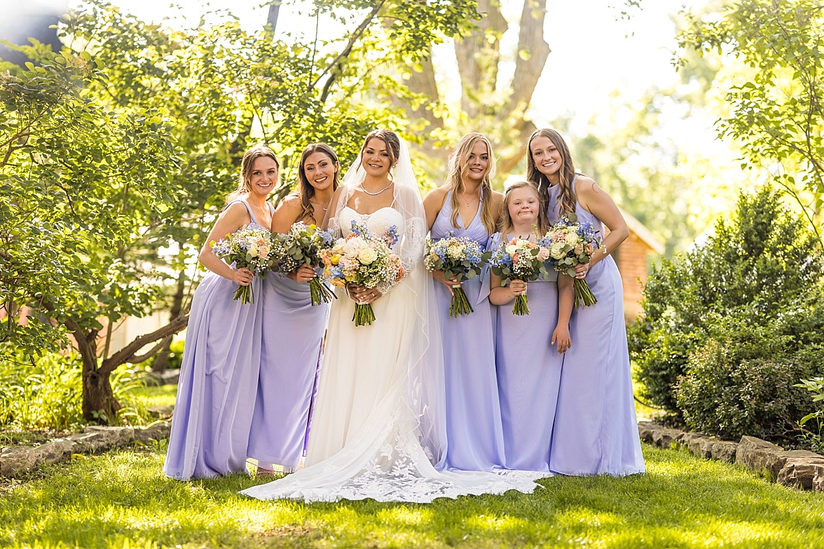 Grace poses with her bridesmaids in a sunny garden in Ste. Genevieve