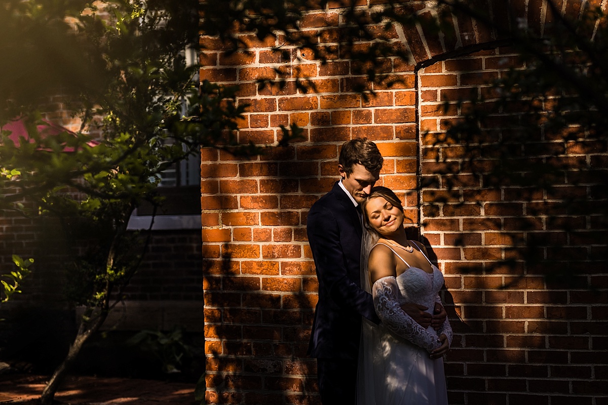 Grace and Alex smile together under the trees during their wedding portraits
