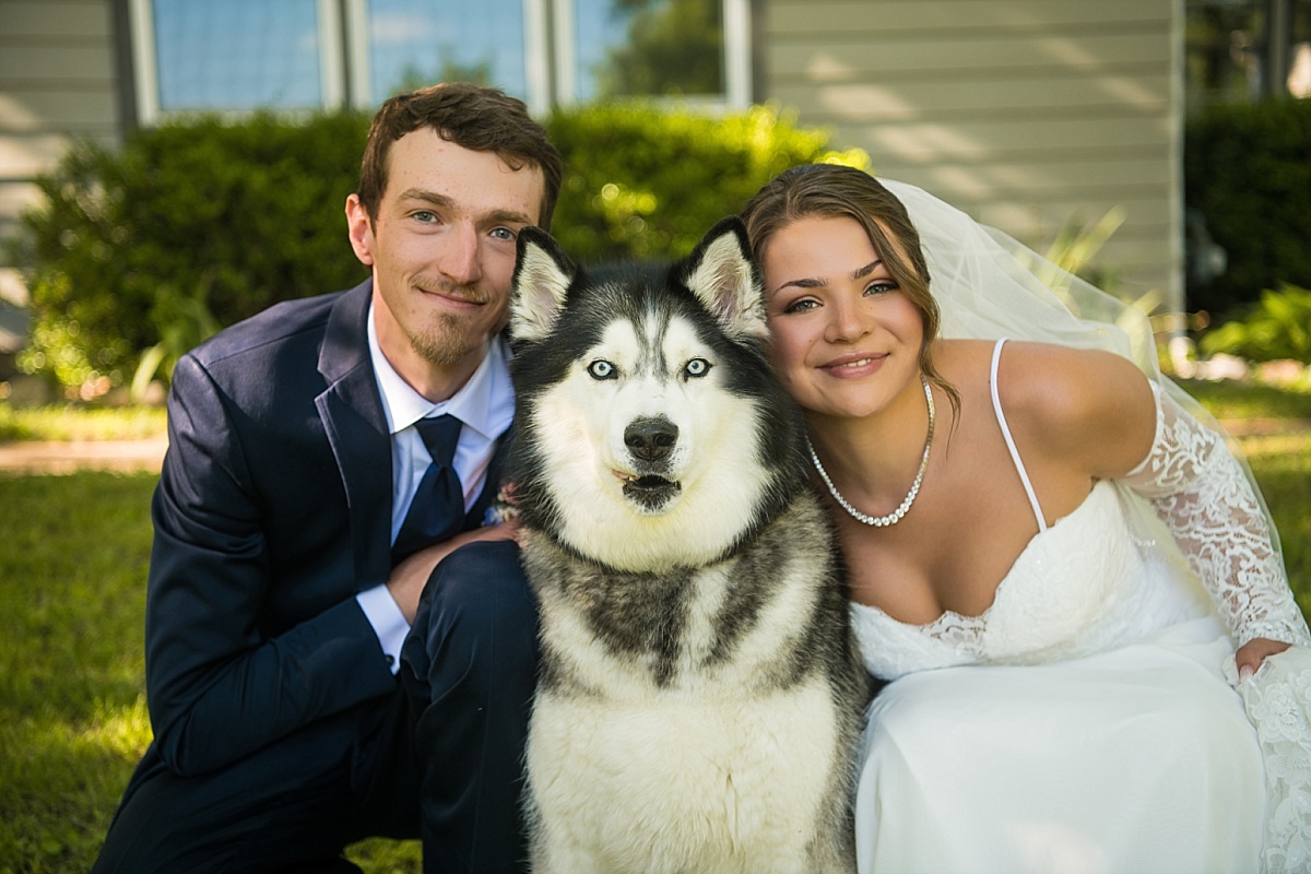 Grace and Alex pose with their husky on their wedding day