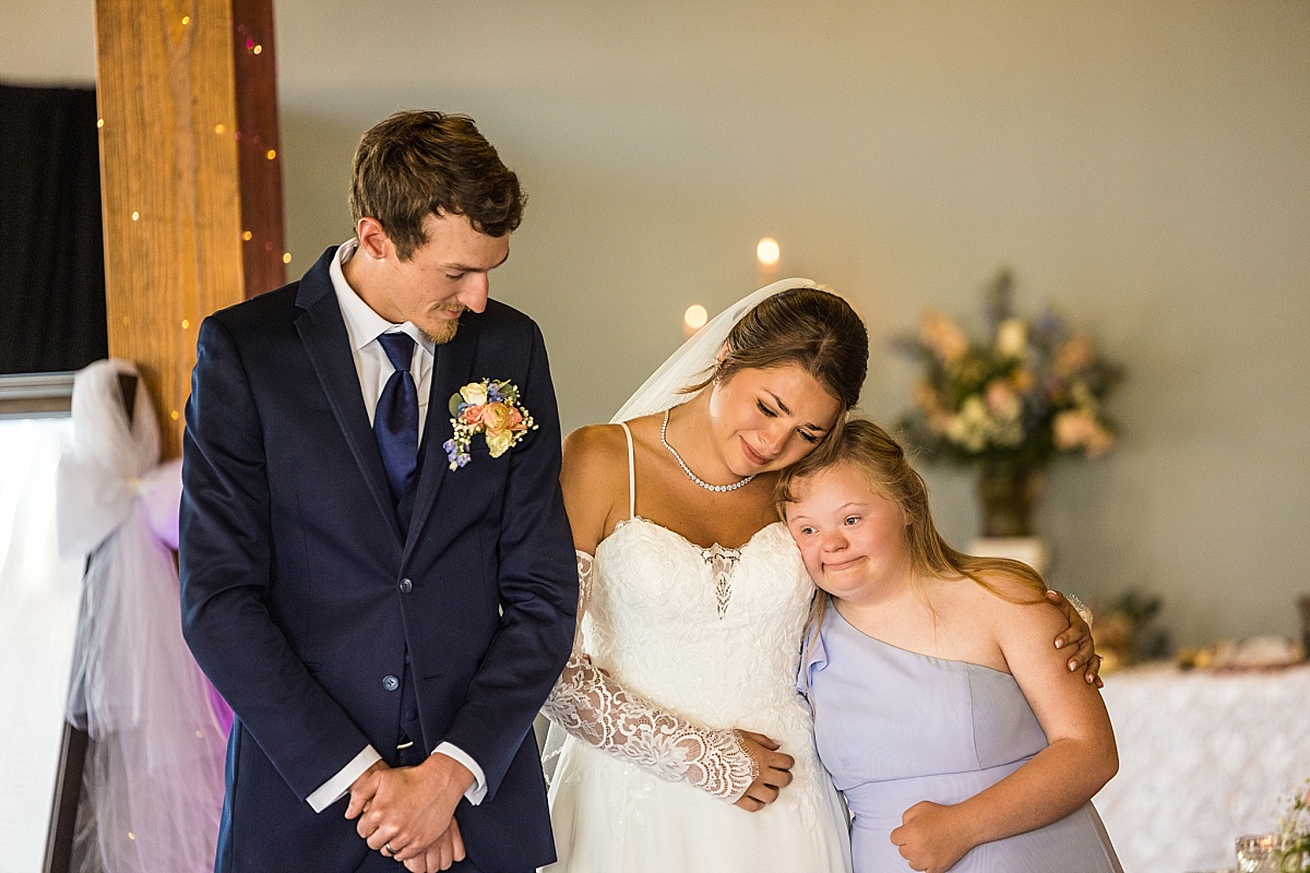 Grace and Alex stand with a young bridesmaid during their wedding reception