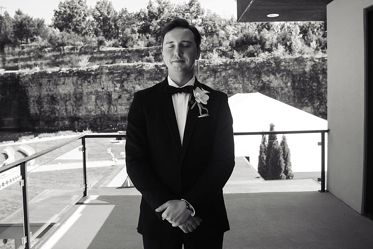 Black-and-white portrait of Justin in his tuxedo overlooking the stone bluffs at Sunset Bluffs.