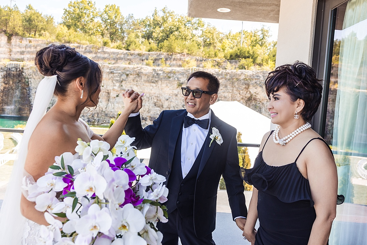 Melicia shares a joyful moment with her parents outside the wedding venue.