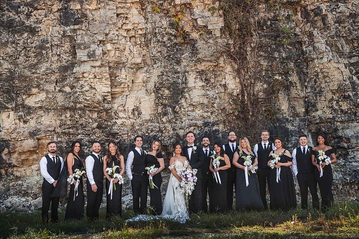 Melicia and Justin pose with their wedding party against the dramatic stone bluffs at Sunset Bluffs.