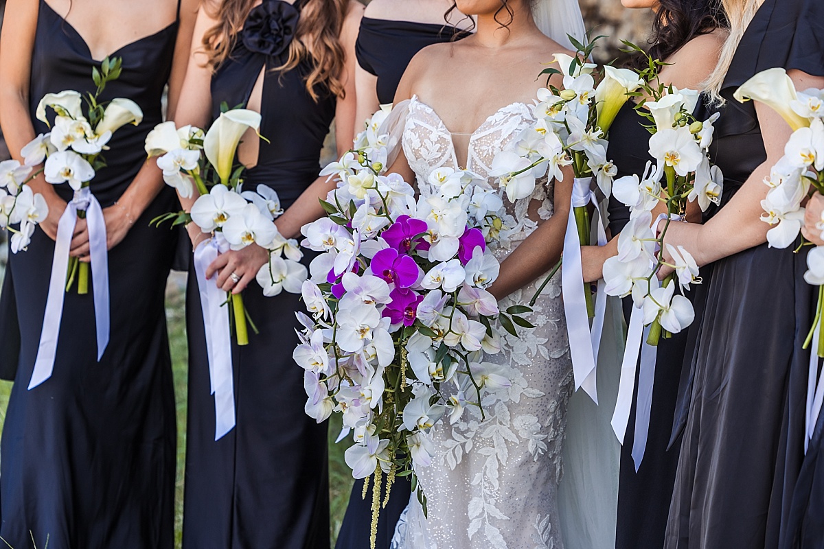 Close-up of Melicia's cascading white and purple orchid bouquet surrounded by her bridesmaids' matching flowers.