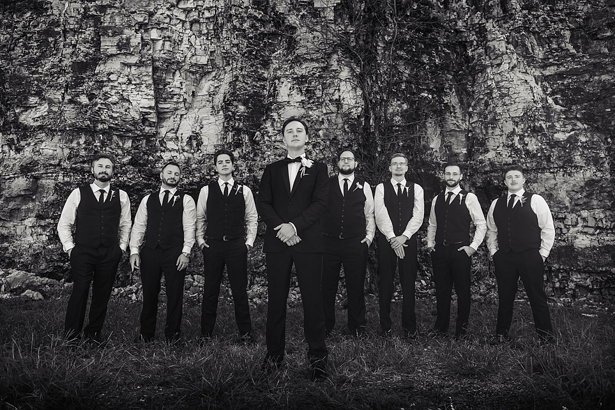 Justin poses with his groomsmen in a black-and-white portrait against the stone bluff backdrop.