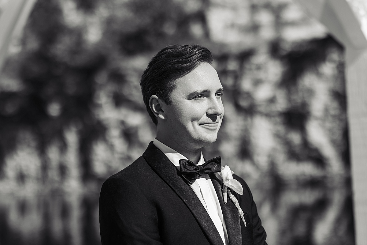 Black-and-white portrait of Justin in his tuxedo against the textured stone bluffs.