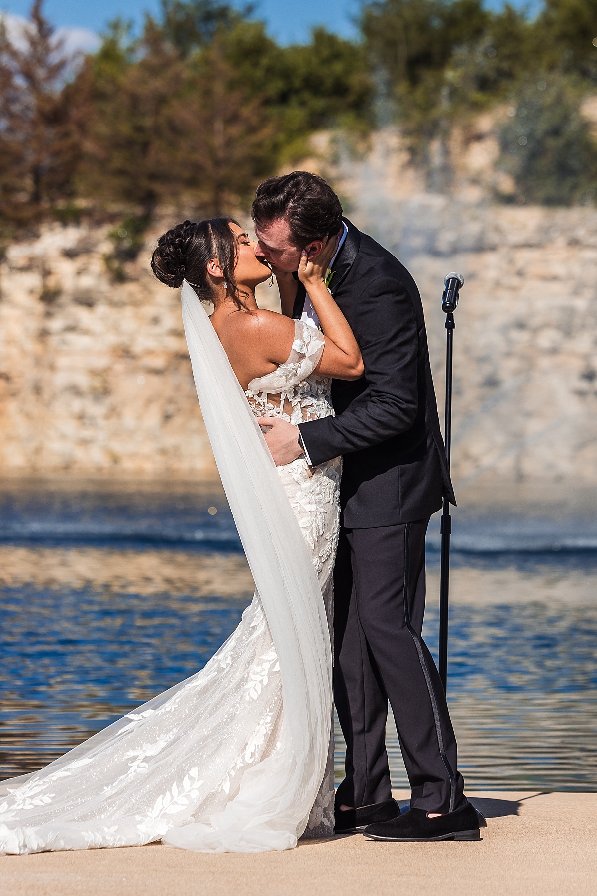 Melicia and Justin share their first kiss as newlyweds beside the lake at Sunset Bluffs.