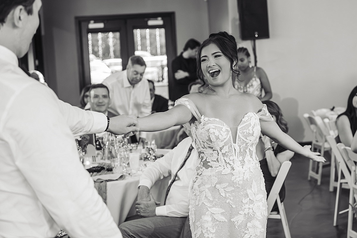Melicia laughs and dances with her arms outstretched during the wedding reception.