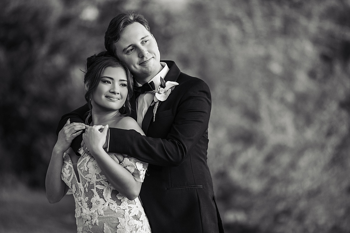 Black-and-white portrait of Melicia and Justin embracing with their heads resting together.