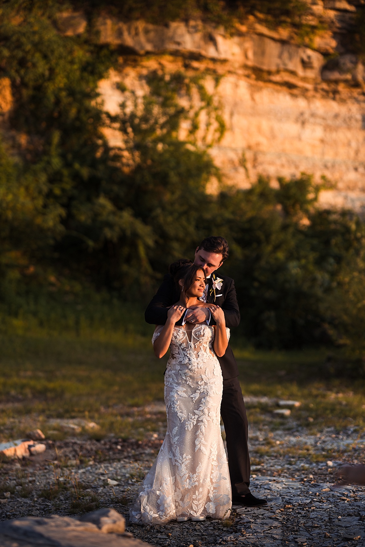 Melicia and Justin embrace in the warm evening light against the glowing stone bluffs.