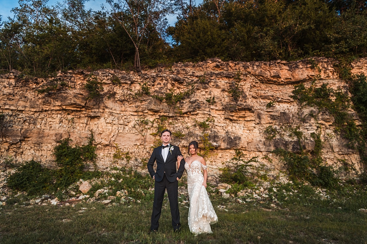 Melicia and Justin stand together in front of the towering limestone cliffs at Sunset Bluffs.