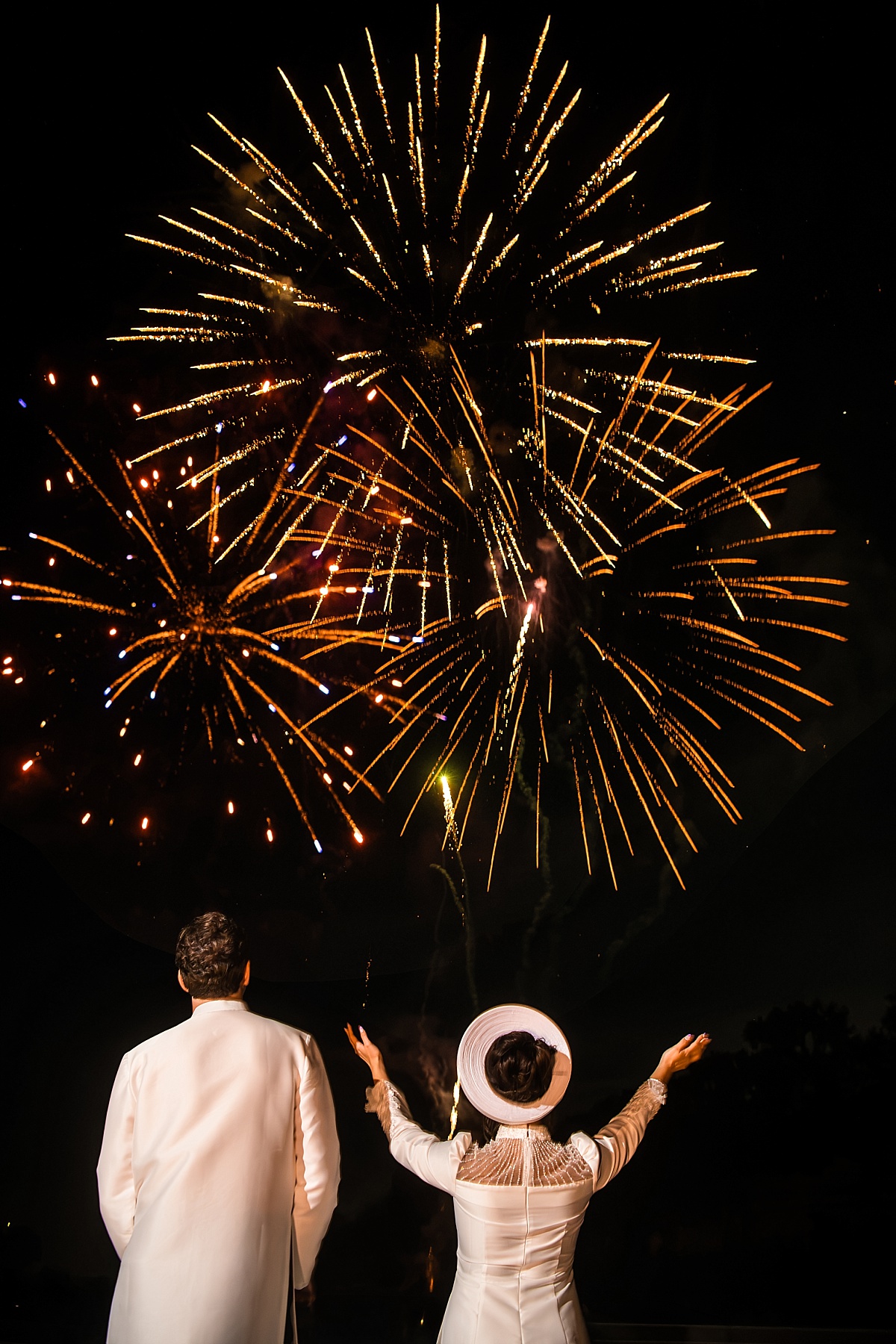 Melicia and Justin watch golden fireworks burst overhead during their wedding celebration.