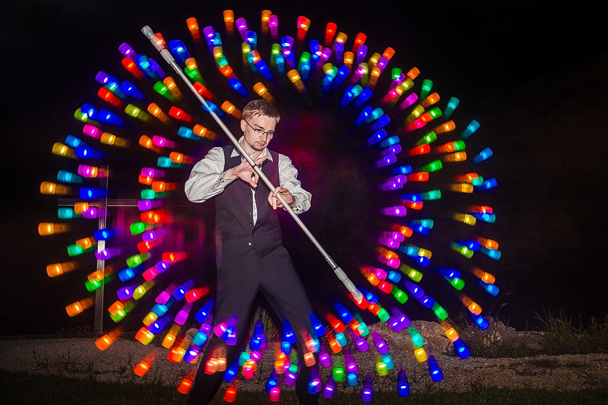 A wedding guest creates a colorful circular light pattern with illuminated props during the couple's reception.