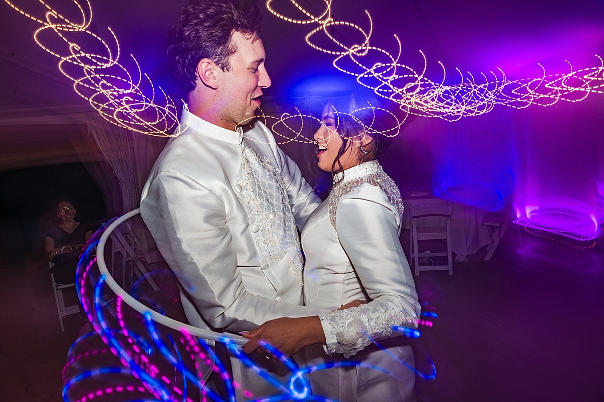 Melicia and Justin embrace in their traditional Vietnamese wedding outfits, surrounded by colorful long-exposure light trails.